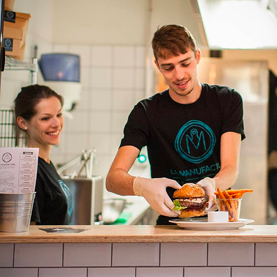Koch von La Manufacture bei der Zubereitung hausgemachter Gourmet-Burger in Basel